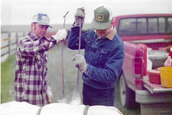 Vintage photo of two ranch hands in work clothes beside a pickup truck
